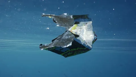 Close-up of plastic packaging from food drifting in dark blue water Stock Footage 237522851
