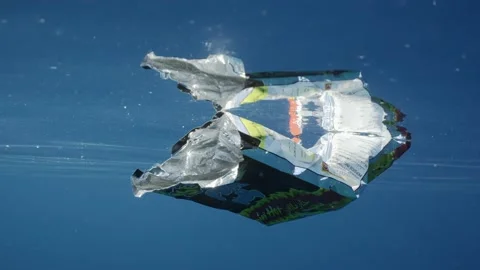 Close up of plastic packaging from food swims in blue water Video stock 236194600