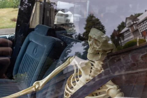 Close up of a plastic skeleton sitting in the driver seat of a vintage blue.. Stockfoto's
