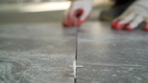Close up of plastic spacer between grey ceramic floor tiles during installa.. Stock Photos