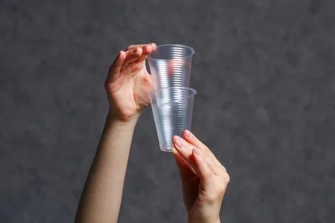 Close-up plastic transparent empty disposable cups in female hands Foto stock