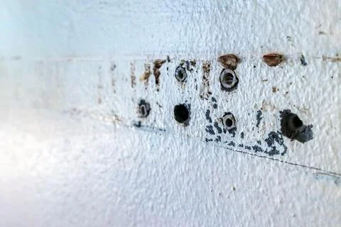 Close up of plastic wall plugs inside drilled holes on dirty concrete wall... Stock Photos