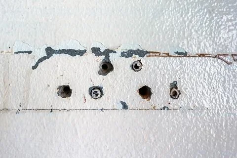 Close up of plastic wall plugs inside drilled holes on dirty concrete wall... Stock Photos
