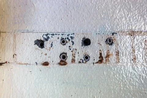 Close up of plastic wall plugs inside drilled holes on dirty concrete wall... Stock Photos