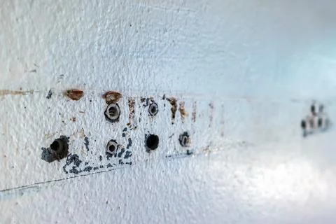 Close up of plastic wall plugs inside drilled holes on dirty concrete wall... Stock Photos