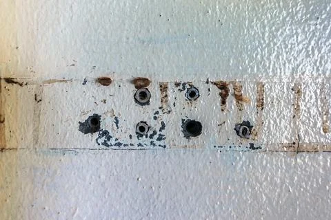Close up of plastic wall plugs inside drilled holes on dirty concrete wall... Stock Photos