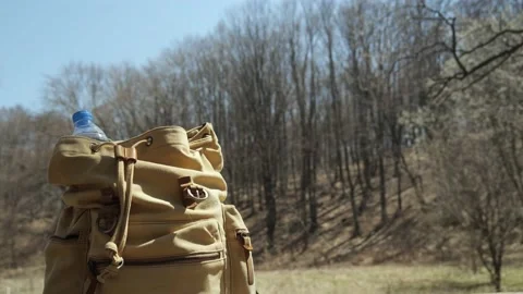 Close up of plastic water bottle in brown canvas hike rucksack in forest Stock Footage 182292369