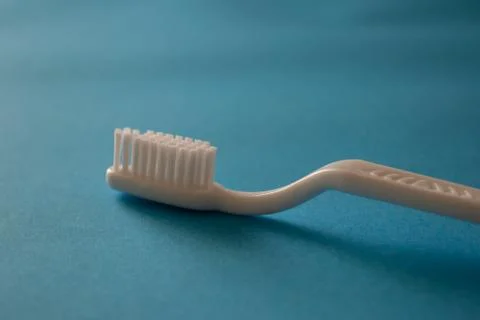 Close up plastic white tooth brush on blue background dental hygiene Stock Photos