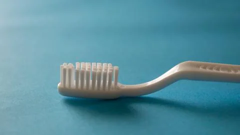 Close up plastic white tooth brush on blue background dental hygiene Stock Photos