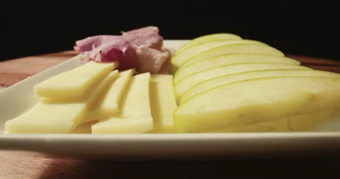 Close up on a plate of appetizers, prosciutto ham, cheese, apple slices. Stock Footage 130696995