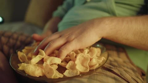 Close up of a plate of chips held by a man taking a serving of the snack at home Stock Footage 315128245