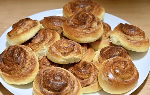 Close-up of a plate piled high with freshly baked golden cinnamon rolls Stock Photos