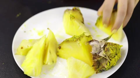 Close-up of a plate with pineapples. Female hands pick up fruits Stock Footage 166600919