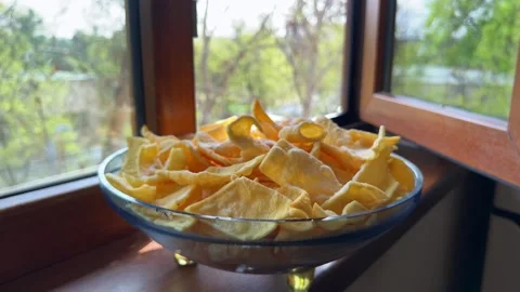Close-up of plate of potato chips on windowsill with garden background Stock Footage 330106323