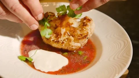 Close-up of a plate with a succulent dish of roasted cauliflower in tomato sauce Stock Footage 194751649