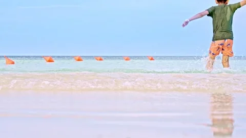 Close up playful kid running on the beach feeling positive emotions slow motion Stock Footage 275553376
