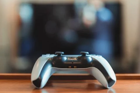 Close up of Playstation 5 (PS5) controller on the table, tv on background, se Stock Photos