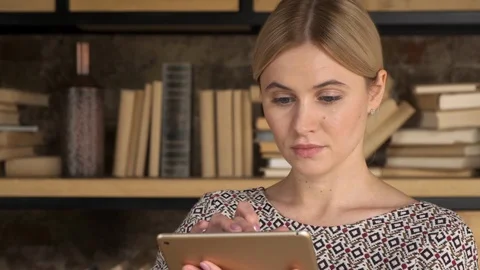 Close up Pleasant woman using tablet on books background. Close up Stock Footage 120010140
