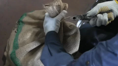 Close up of pliers securing a metal fastener onto a burlap sack filled with Stockbeeldmateriaal 339123361