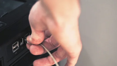 Close-up plug in usb to black computer. White usb cords hanging from the tower Видео 101373323