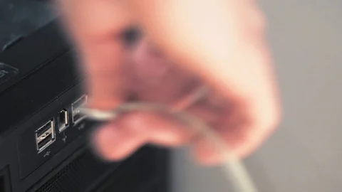 Close-up plug in usb to black computer. White usb cords hanging from the tower Видео 101373355