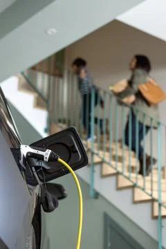 Close-up of Plugged cable charging an electric family car in a particular garage Foto stock