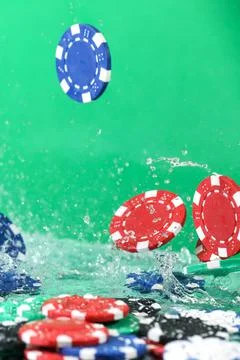 Close up of poker playing chips falling on a green table under the water drop Foto stock