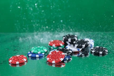 Close up of poker playing chips falling on a green table under the water drop Foto stock