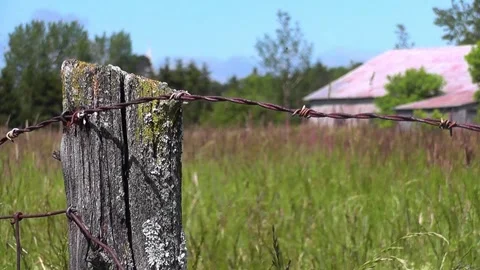 Close-up on a pole fence with barbed wire near a field in the countryside on Stock Footage 166331144