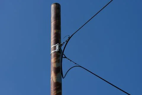 Close-up of a pole with optical cable fixed on it against blue sky. Stock Photos