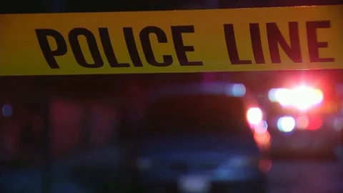 Close up of Police Crime Tape with Police Lights in background Stock Footage