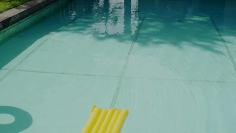 Close up of pool with inflatable rubber loungers on water surface in slow motion Stock Footage 128965600