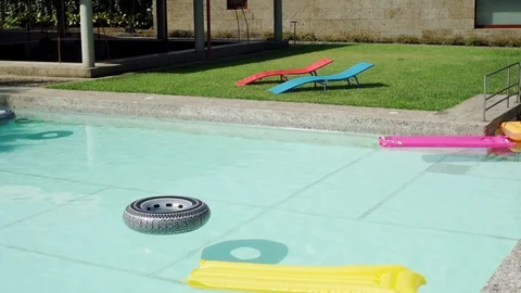 Close up of pool with inflatable rubber loungers on water surface in slow motion Stock Footage 128965769