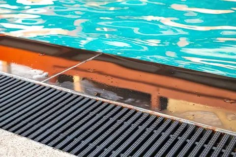 Close-up of poolside deck with water and wooden railing Фото