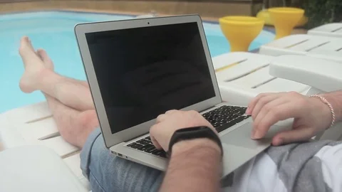 Close-up of poolside male freelancer is working on a project for laptop. Stock Footage 85274828