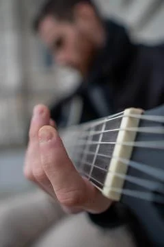 Close-up of the poorly manicured hands of a bearded man learning to play th.. Stock Photos