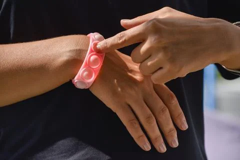 Close-up of a popit and simple dimple toy. A bracelet on a woman's hand in th Foto stock
