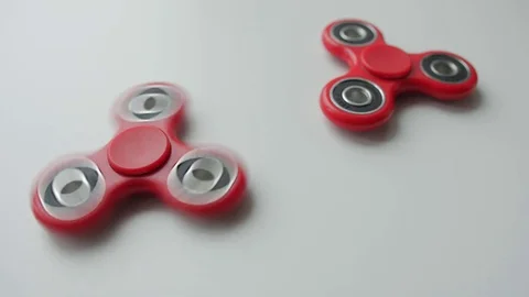 Close up of popular toy fidget spinner rotating over white background Stock Footage 78675829
