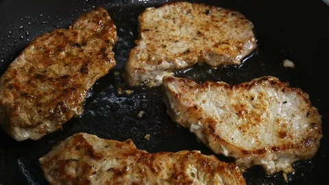 Close-up of pork chops are fried in a frying pan. Pork chops in a skillet Stock Footage 102770070