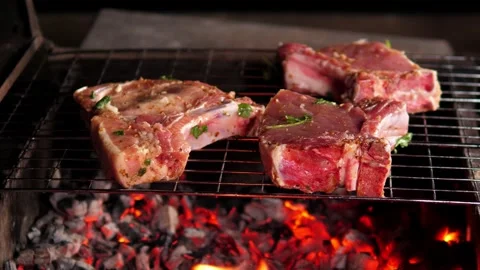 A close-up of a pork steak being grilled on hot coals, a man turns the meat. Stock Footage 295191649