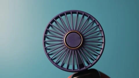 Close-up of a portable purple fan with a gold accent against a blue background Stock Footage 340268039