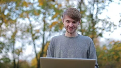Close up portait of a man using laptop outdoors in the park in autumn Stock Footage 70430000