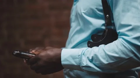 Close up portrait of african cop putting gun in holsters isolated over brick Stock Footage 142804500