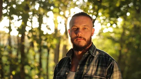 Close up portrait of attractive man with beard, back in the forest between trees Stock Footage 126496234