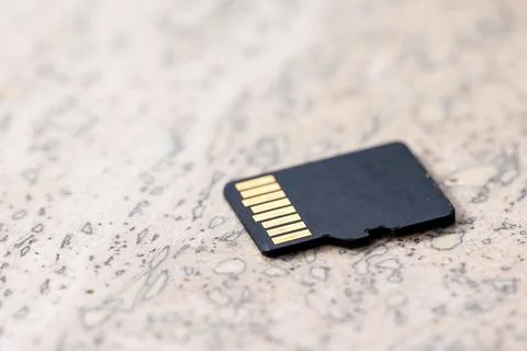 A close up portrait of the back of a black micro SD card lying on a stone sur Stock Photos
