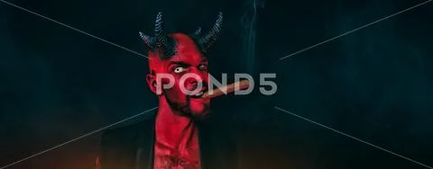 A close-up portrait of a bad demon with a cigar. Horror movie, nightmare. Hal Stock Photos