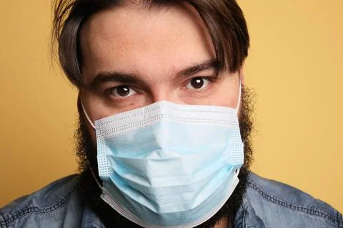 Close-up portrait of bearded guy wearing breathing mask. Isolated yellow wall. Stockfoto's