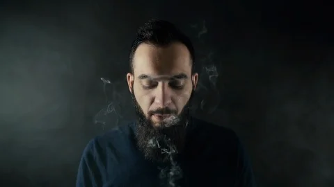 Close-up portrait of bearded man vaping many small steam circles to camera Stock Footage 111525519