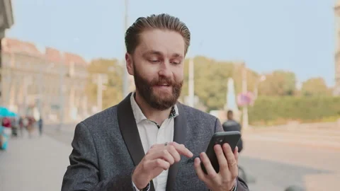 Close up portrait bearded man walking use phone read good news on city street Stock Footage 140479178
