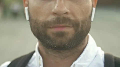 Close-up. Portrait of a bearded middle-aged man with wireless headphones in his Stock Footage 197508298
